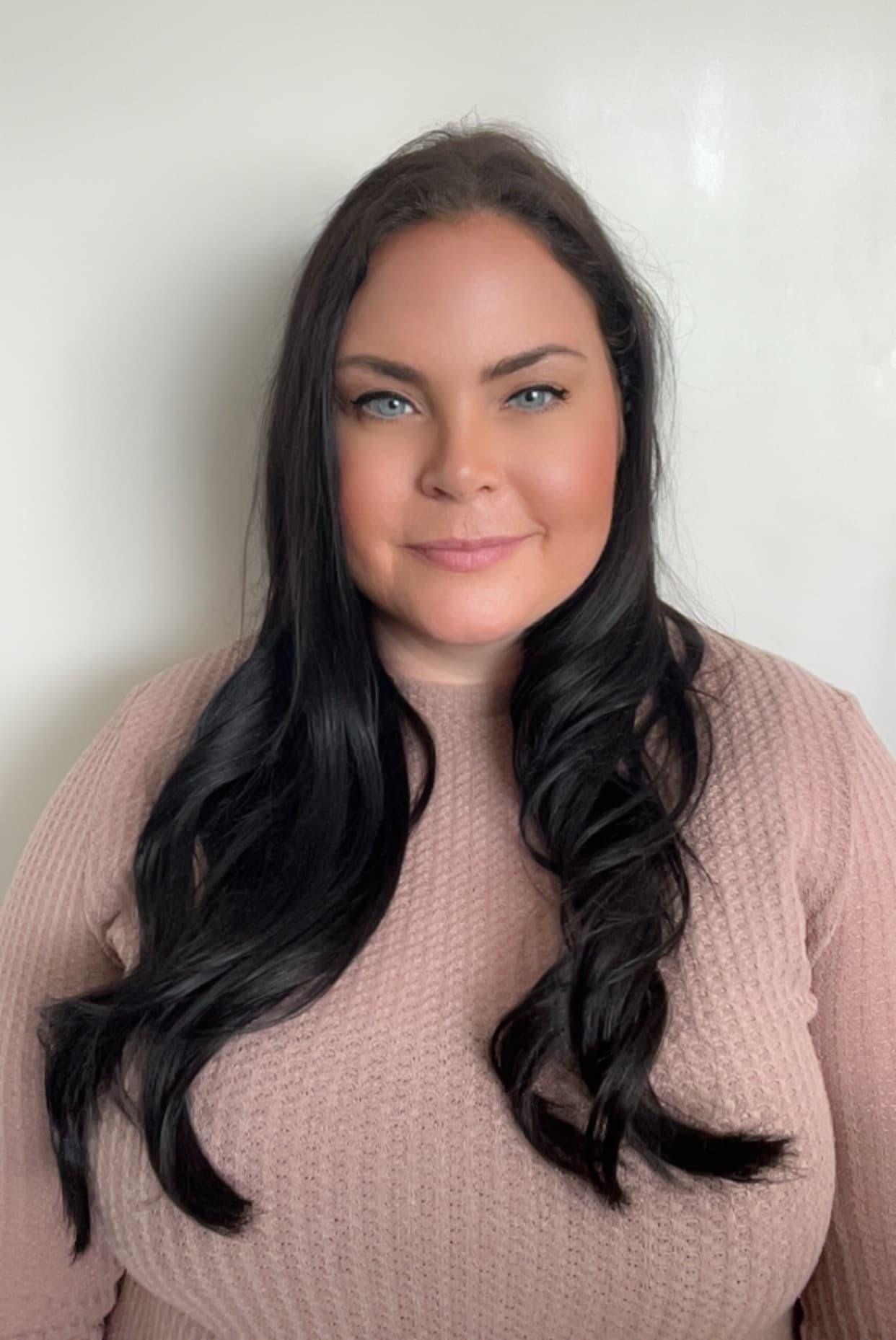Portrait of Esther, founder of Essy’s Essentials, wearing a soft blush knit against a neutral background.