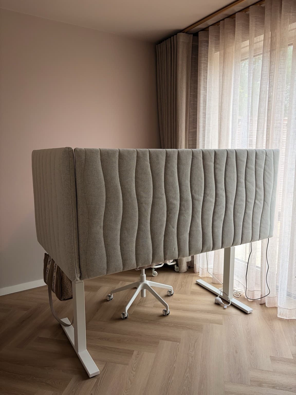 Esther’s home office behind a pale upholstered desk screen, beside the living room curtains.